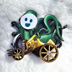 May include: A green and gold steampunk-style creature with a smiling face, riding a small, detailed, gold and black vehicle with wheels.