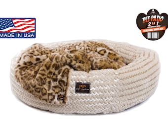 May include: A beige and white pet bed with a removable inner bed. The bed has a leopard print fur insert. The bed is made in the USA. The tag reads "Pet Patio 2 in 1 Removable Inner Bed".