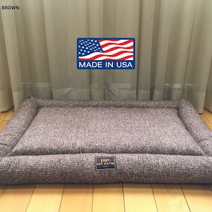 May include: A brown rectangular dog bed with a raised edge and a "Pet Patio" logo. The bed is made in the USA.
