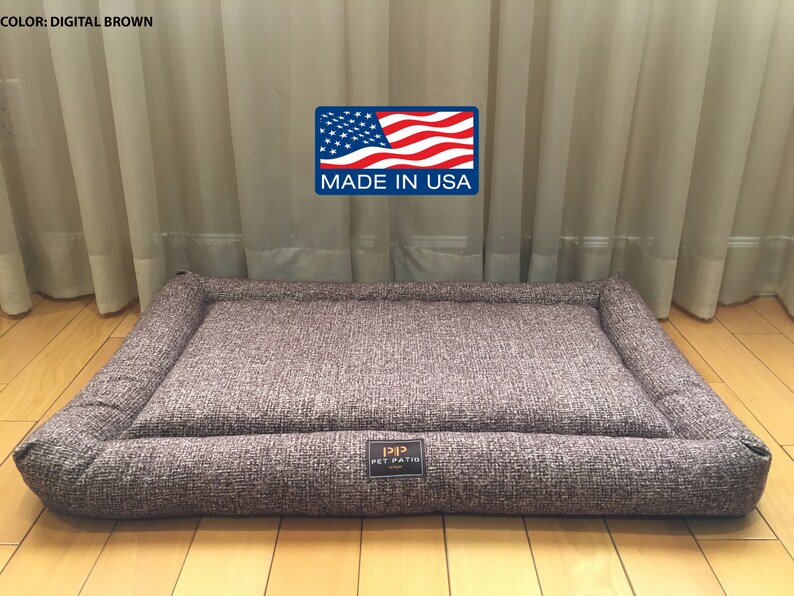 May include: A brown rectangular dog bed with a raised edge and a "Pet Patio" logo. The bed is made in the USA.