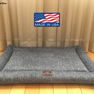 May include: A gray rectangular dog bed with a raised edge and a "1212 Pet Patio" logo. The bed is made in the USA.