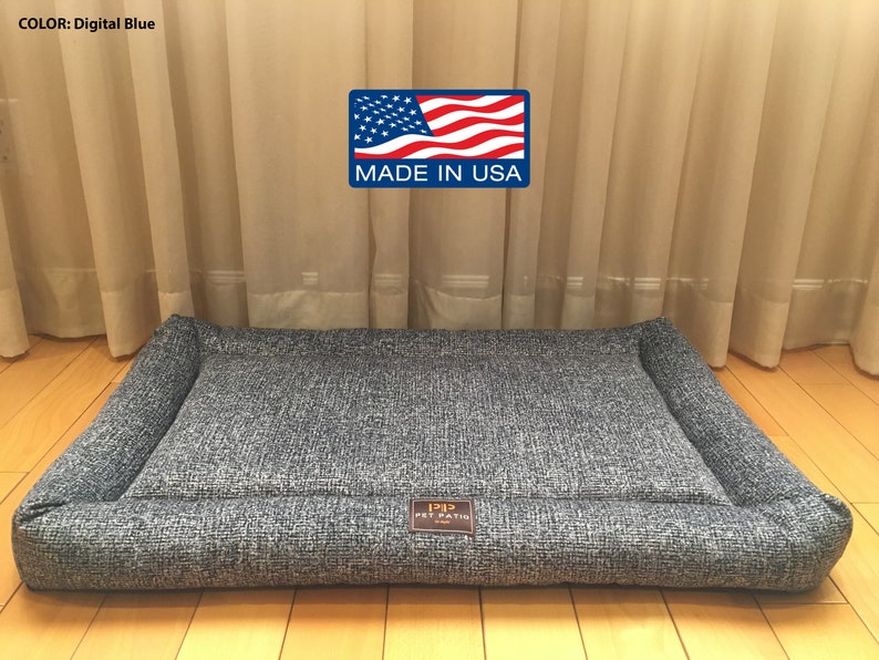 May include: A gray rectangular dog bed with a raised edge and a "1212 Pet Patio" logo. The bed is made in the USA.