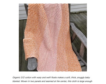 May include: Waffle weave baby blanket in shades of orange and pink, draped over a wooden chair. The blanket is made of soft, textured cotton and features the text "Waffle Weave Baby Blanket" and the name "Christine Jablonski".