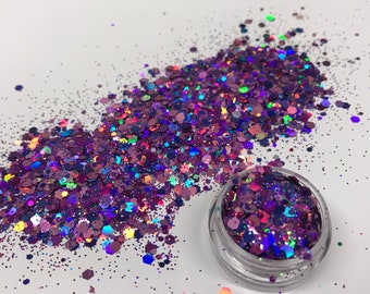 May include: A small jar of iridescent purple glitter with a variety of sizes and shapes. The glitter is scattered on a white surface.