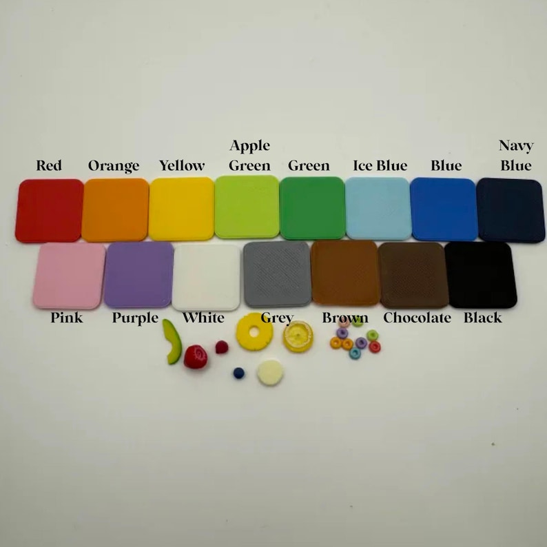May include: A collection of colorful square tiles in various shades, including red, orange, yellow, green, blue, and black. Additional small decorative elements like fruit and beads are also present. The colors are labeled with text.
