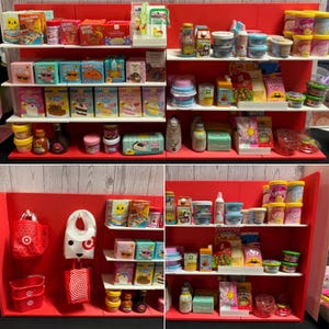 May include: Miniature grocery store display with shelves stocked with tiny food products, including cereal boxes, cake mixes, and dairy items. The display features a red backdrop and white shelves, creating a colorful and playful scene.