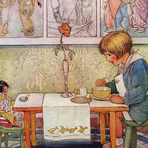 Puede incluir: Una niña pequeña está sentada a una mesa con un tazón de sopa frente a ella. La mesa tiene un mantel blanco con una fila de patitos amarillos bordados. Hay imágenes en la pared detrás de ella.