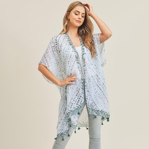 May include: A white sheer kimono with a green and blue geometric pattern and tassel trim.