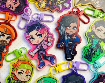 May include: A collection of colorful acrylic keychains featuring cartoon characters. Each keychain has a unique design with vibrant colors and attached metal clasps. The keychains are in various shapes and sizes, showcasing different characters.