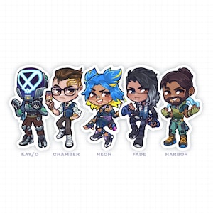 Puede incluir: Cinco personajes de dibujos animados del videojuego Valorant. Los personajes son Kay/O, Chamber, Neon, Fade y Harbor. Cada personaje est&aacute; representado en un estilo chibi con una cabeza grande y un cuerpo peque&ntilde;o. Los personajes llevan todos sus atuendos y armas caracter&iacute;sticos. El fondo es una cuadr&iacute;cula blanca.