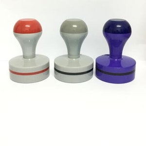 May include: Three rubber stamps with different colored tops: red, gray, and blue. Each stamp has a black base and a black ring around the top.