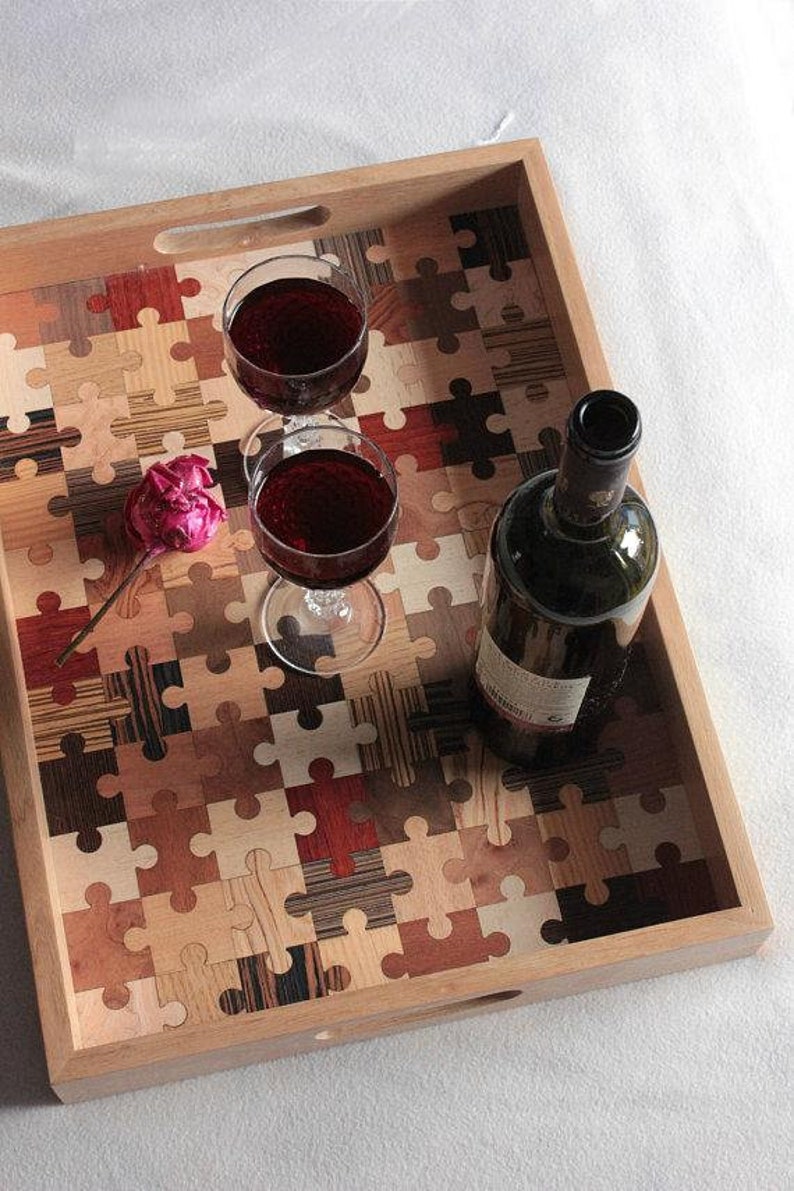 K&ouml;nnte beinhalten: Ein Holztablett mit einem Puzzle-Design aus verschiedenen Holzarten. Das Tablett hat zwei Griffe und ist mit zwei Gl&auml;sern Rotwein und einer Flasche Rotwein gef&uuml;llt.
