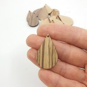 May include: A set of wooden teardrop shapes with a hole at the top. The teardrops are made of wood with a natural wood grain pattern.