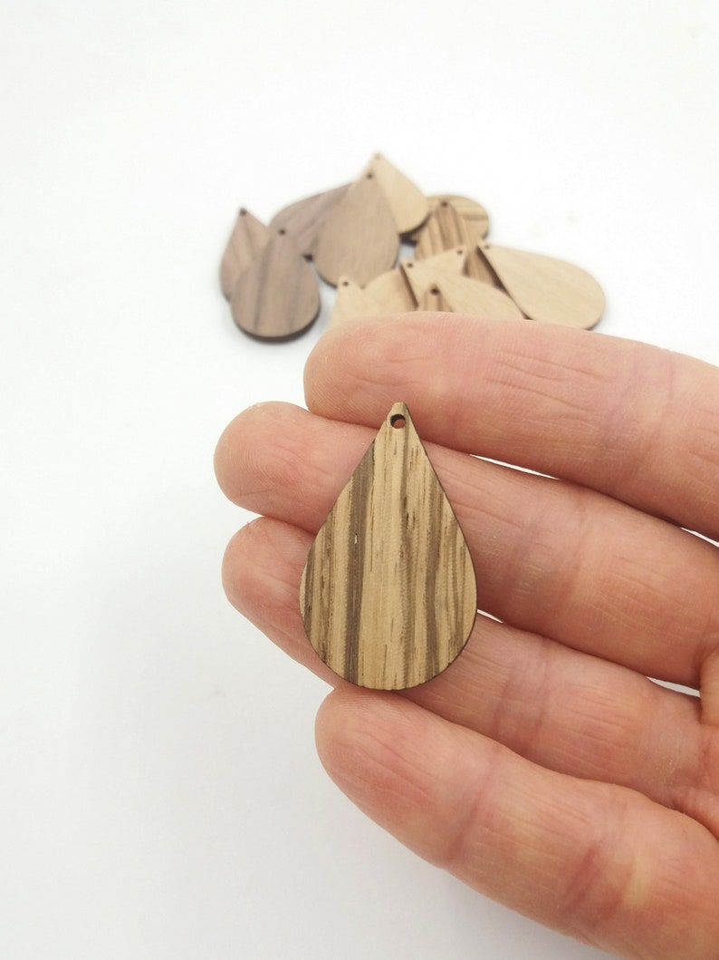 May include: A set of wooden teardrop shapes with a hole at the top. The teardrops are made of wood with a natural wood grain pattern.