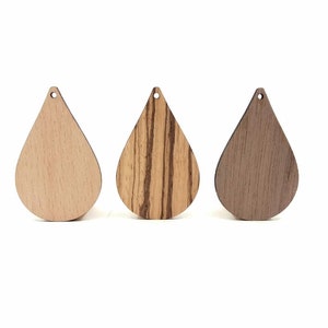 May include: Three wooden teardrop-shaped pendants in different wood finishes: light wood, striped wood, and dark wood.