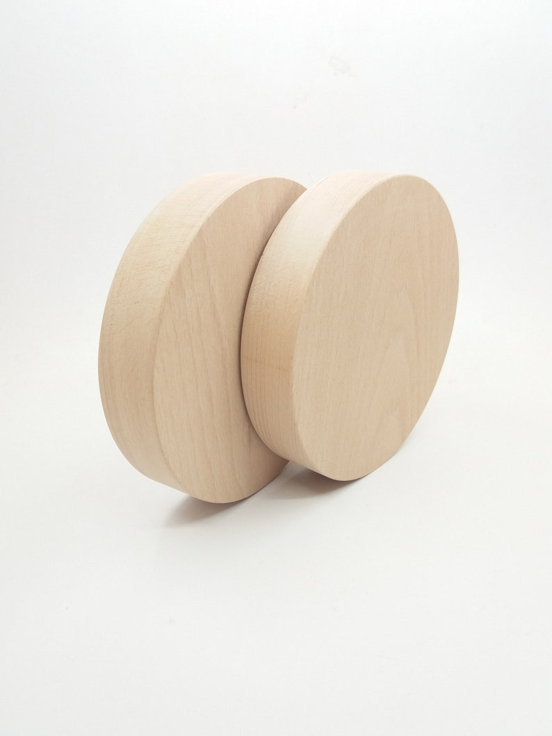May include: Two unfinished wooden circles, one slightly larger than the other, are stacked on top of each other. The circles are light brown in color and have a smooth, polished surface.