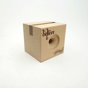 May include: A wooden phone stand with a cutout for a phone and the words "believe in your dream" engraved on the front.