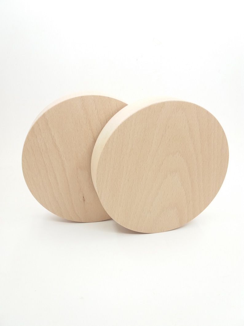 May include: Two unfinished, round wooden discs, stacked on top of each other. The discs are light brown in color and have a smooth surface.