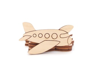 May include: A wooden airplane cutout with a light brown finish. The airplane has wings, a tail, and four circular windows. It is sitting on a stack of similar wooden pieces, likely coasters or decorative elements.