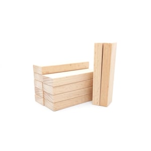 Peut inclure: Un ensemble de blocs de bois de couleur claire, certains empilés et d'autres debout. Les blocs sont rectangulaires et semblent être inachevés. L'arrière-plan est blanc.