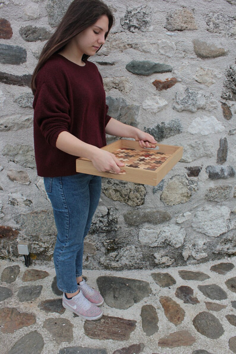 K&ouml;nnte beinhalten: Ein Serviertablett aus Holz mit einem einzigartigen Design aus kleinen Holzst&uuml;cken. Das Tablett hat zwei Griffe an den Seiten und wird von einer Person gehalten.