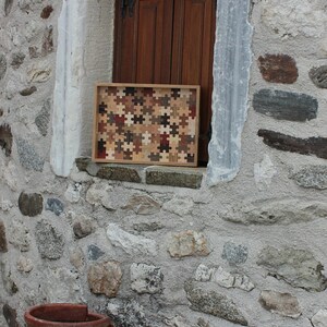 K&ouml;nnte beinhalten: Ein Tablett aus Holz, das aus kleinen Puzzleteilen in verschiedenen Braunt&ouml;nen, Beige und Rot besteht. Das Tablett liegt auf einer Steinmauer mit einem Fenster dahinter.