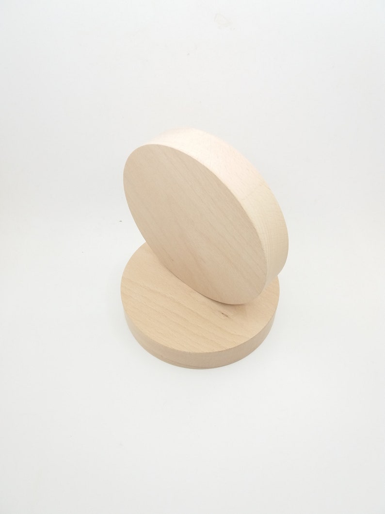 May include: Two unfinished wooden circles stacked on top of each other. The circles are light brown in color and have a smooth surface.