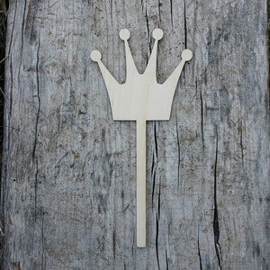 May include: A wooden crown cutout with a stick attached to the bottom. The crown is light brown and has five points.