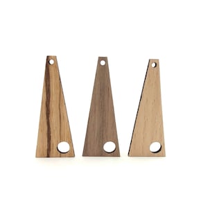 Puede incluir: Tres colgantes de madera en forma de triángulo con un agujero en el centro. Los colgantes están hechos de diferentes tipos de madera, cada uno con un patrón de veta único.