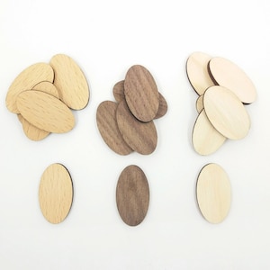 Può includere: Tre pile di sagome ovali in legno per artigianato. La prima pila è di colore marrone chiaro, la seconda pila è di colore marrone scuro e la terza pila è di una tonalità di marrone più chiara. Ogni pila ha un'unica sagoma davanti.