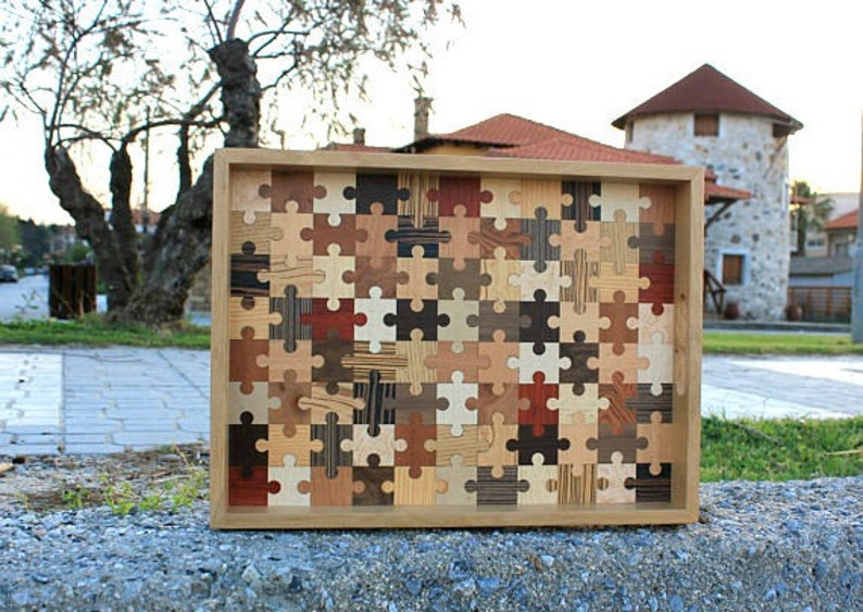 K&ouml;nnte beinhalten: Ein Tablett aus Holz mit einem Puzzle-Design aus verschiedenen Holzarten. Das Tablett ist aus Naturholz gefertigt und hat eine hellbraune Farbe.