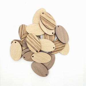 May include: A pile of wooden oval-shaped tags with a hole at the top. The tags are made of light and dark wood with a striped pattern.