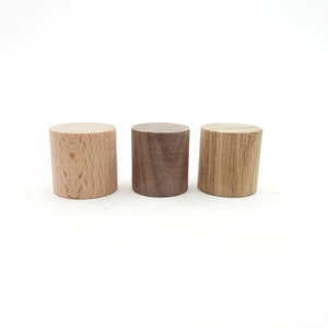 Peut inclure: Trois cylindres en bois de diff&eacute;rents types de bois. Le cylindre de gauche est brun clair, le cylindre du milieu est brun fonc&eacute; et le cylindre de droite est brun clair avec un motif de grain.