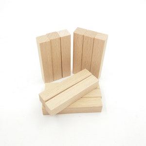 Könnte beinhalten: Ein Satz von acht unbehandelten Holzblöcken, perfekt für Bastelarbeiten oder DIY-Projekte. Die Blöcke sind rechteckig und haben eine natürliche Holzfarbe.