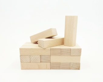 Puede incluir: Un juego de bloques de madera clara. Algunos bloques están apilados, otros esparcidos encima. Los bloques rectangulares son de tamaño uniforme, perfectos para un juego de habilidad y estrategia. El juego está diseñado para varios jugadores.