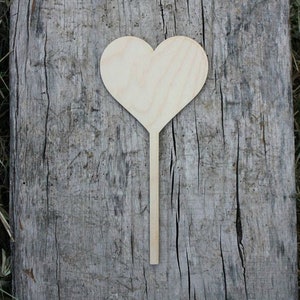 May include: A wooden heart-shaped sign on a stick. The sign is blank and ready to be decorated.