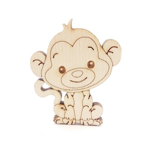 Puede incluir: Recorte de madera de un mono sonriente, con grandes orejas y una cola enroscada. El mono es de color marrón claro con contornos y detalles en marrón oscuro. El recorte es probablemente para manualidades o decoraciones.