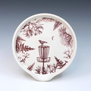 May include: A set of three ceramic mugs with a speckled, matte finish. The mugs are in shades of cream, light brown, and dark brown. Each mug has a simple, minimalist design and a rounded handle.