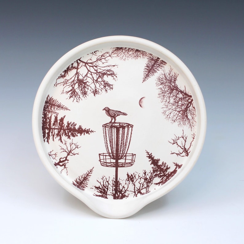 May include: A set of three ceramic mugs with a speckled, matte finish. The mugs are in shades of cream, light brown, and dark brown. Each mug has a simple, minimalist design and a rounded handle.