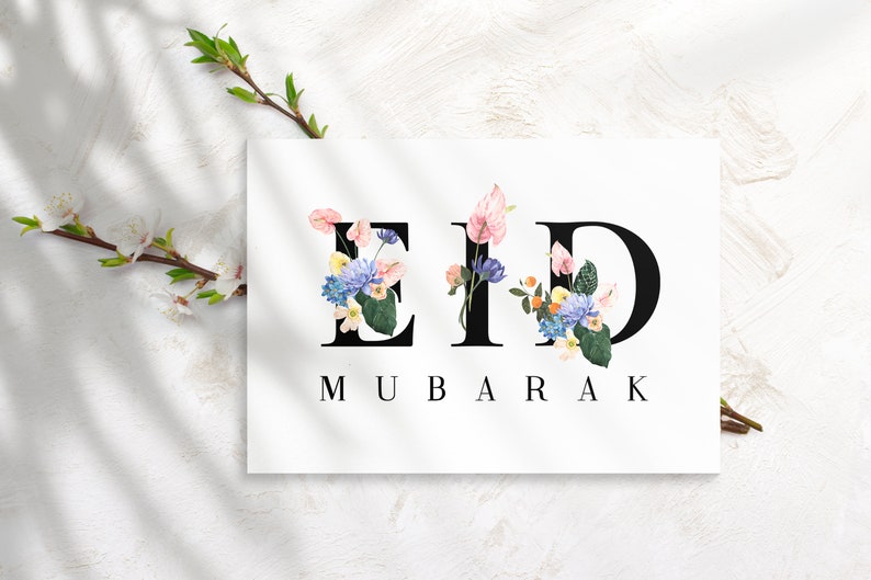 May include: A white card with the words "Eid Mubarak" in black lettering. The letters are decorated with colorful flowers.