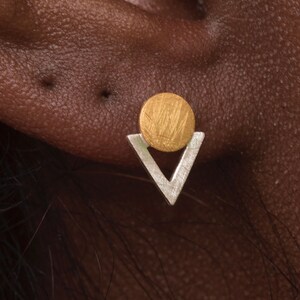 May include: Gold and silver geometric earrings with a circle and triangle design.