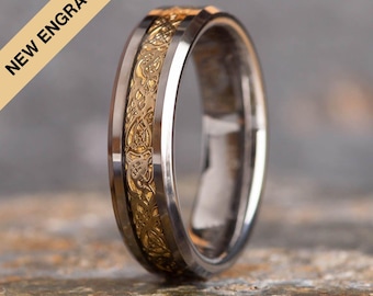 Könnte beinhalten: Ein silberner und goldener Ehering mit einem keltischen Knotendesign. Der Ring ist abgeschrägt und hat eine polierte Oberfläche.