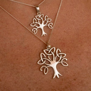 Puede incluir: Dos collares de plata con un diseño de árbol de la vida de nudo celta. El collar más grande está en una cadena de plata y el collar más pequeño está en una cadena de plata.