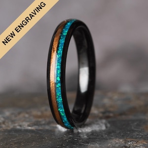 以下が含まれることがあります： 銅と青いオパールのインレイが施された薄いバンドが付いた、黒いタングステンカーバイド製のリング。