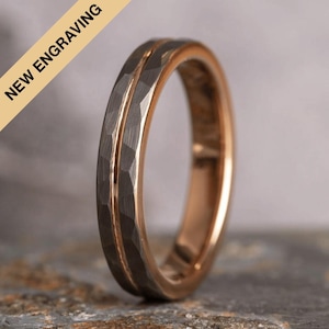 May include: A silver and rose gold wedding band with a hammered finish. The band has a thin rose gold inlay.