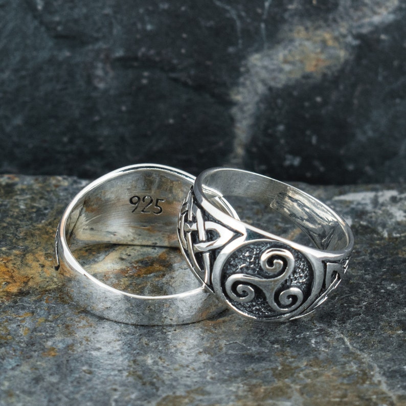 May include: Two silver rings, one with a Celtic knot design and the other with the inscription "925".