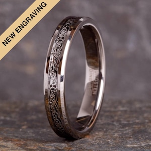 May include: A silver tungsten ring with a Celtic knot design engraved on the band. The ring is polished and has a beveled edge.