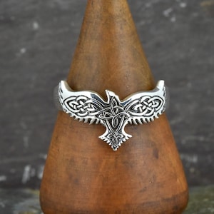 May include: A silver ring with a Celtic knot design featuring a stylized eagle. The eagle's wings are spread and the knotwork is intricate.