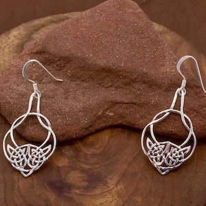 May include: A pair of silver Celtic knot earrings with a dangling design. The earrings are made of a silver metal and have a detailed knot pattern.