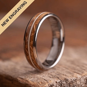 May include: A brown wood and silver ring with a thin silver band and a wood inlay. The wood inlay has a light brown colour and a subtle pattern.